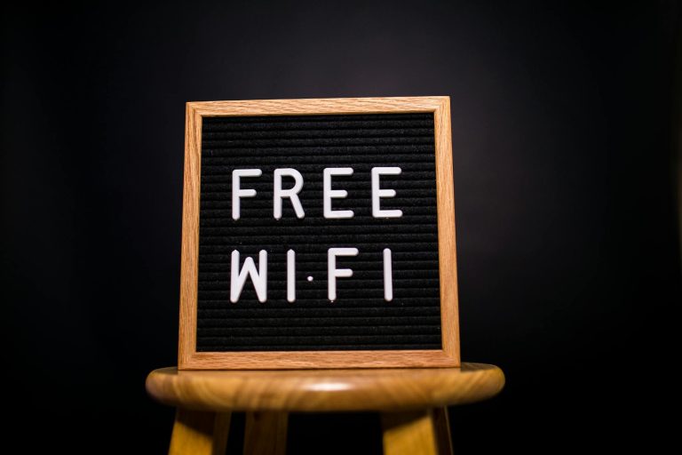 A wooden frame sign with 'Free Wi-Fi' text displayed on a stool in a dark room.